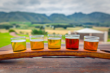 Beer tasting glasses on a wooden tray outside the brewery with a beautiful view of the mountains in South Africa