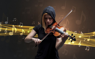 Fototapeta premium Young male musician playing on his violin with musical notes around