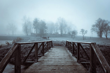 wooden bridge over pond in the fog