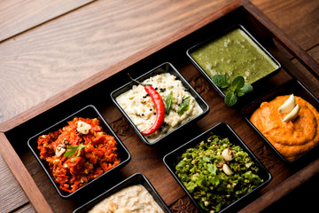Group of Indian Chutneys includes coconut, Peanut, green and red chilly, garlic and pudina served in small square shape bowls. selective focus