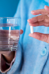 Senior woman taking pill with a glass of water, concept of medication and health