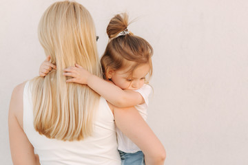 Beautiful mothe with her daughter. Blond hair female. Gray background. Best friends