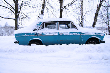 Vehicles covered with snow in the winter blizzard in the parking. Cars in snowdrifts after a snowfall. After the winter storm