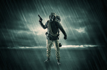 Terrorist in a stormy space with gas mask on his hand and weapons on his arm
