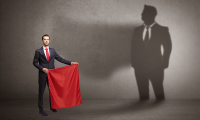 Fototapeta premium Businessman standing with red cloth on his hand and his shadow on the background 