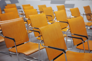 Rows of yellow chairs in a conference room. Space for public speaking.