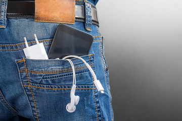 phone charging, smartphone, headphones in jeans pocket. Battery Charger, technology in everyday life. battery fast discharge concept