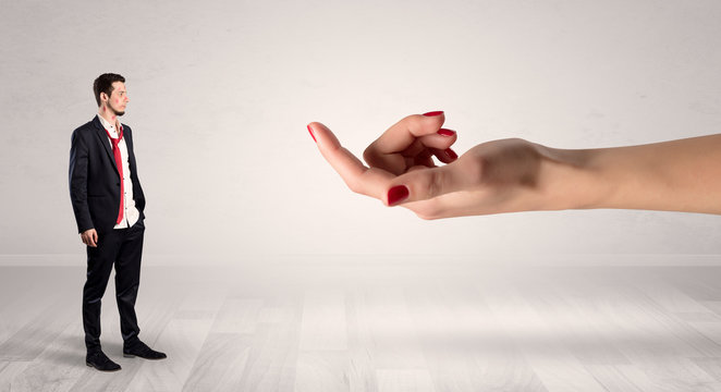 Businessman with kisses on his face in an empty space where a big hand baiting him
