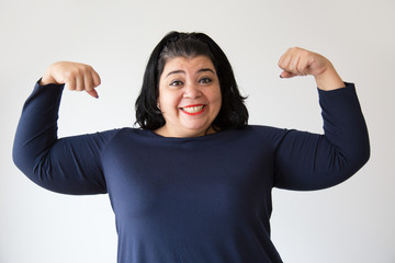 Successful Hispanic woman holding fists up and smiling at camera. Beautiful positive overweight...