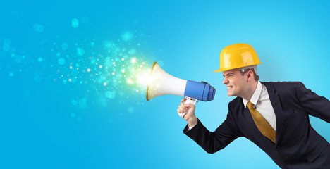 Fototapeta premium Young architect constructor yelling with megaphone and sparkling sounds 