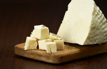 Pieces of delicate white cheese on a wooden plank.