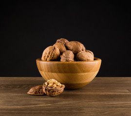 Walnuts in wooden Bowl on isolated on black background, centered, design
