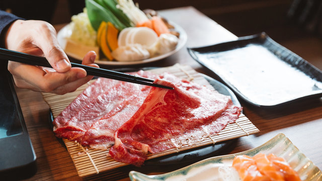 Man Holding Rare Slice Wagyu A5 Beef By Chopsticks For Boiling In Shabu Hot Pot.  