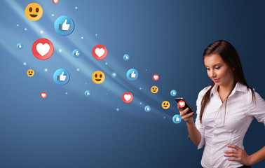 Young person using smartphone with flying social media icons around
