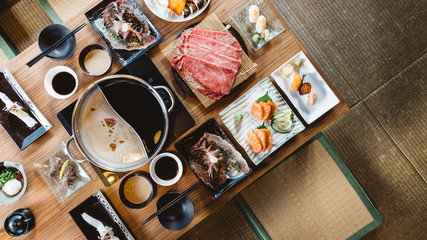 Top view of Shabu set including rare slices Wagyu A5 beef, Shabu shoyu and clear base, salmon, sushi and vegetables. 