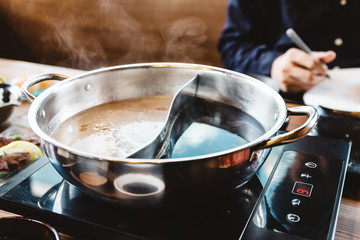 Shabu broth: Shoyu soup base and clear soup base in hot pot with steam that ready for boiling beef and vegetables. 