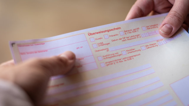 Arzt &uuml;bergibt &Uuml;berweisungsschein