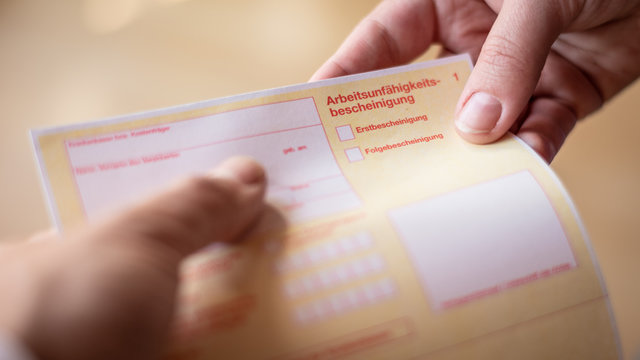 Arzt &uuml;bergibt Arbeitsunf&auml;higkeitsbescheinigung
