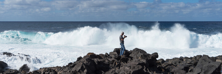 Old man photographs big waves on the coast of Lanzarote. Canary Islands