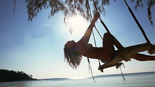 Beautiful happy girl in sunglasses and bikini relax on the swing at the beach. slow motion, 1920x1080