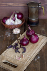Red onion and garlic with basil on the old wooden background.