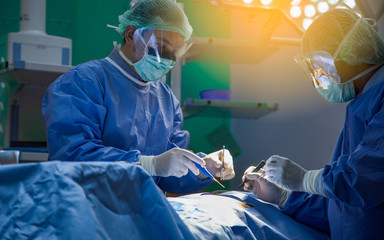 Several surgeons surrounding patient on operation table during their work.Medical team performing an operation in the surgery room, in a hospital.