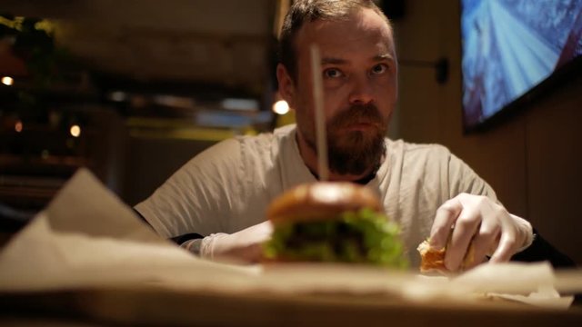 man with beard eating burger. cheeseburger