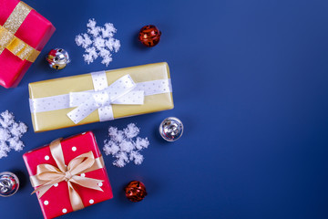 Festive composition with colorful Christmas presents wrapped in bright paper tied with bow on solid blue background. New year themed flat lay with festive attributes. Close up, copy space.
