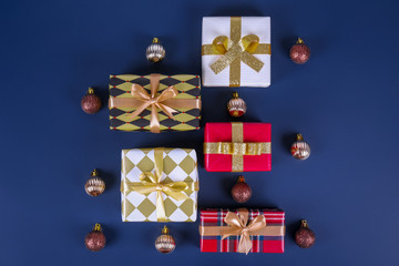 Festive composition with colorful Christmas presents wrapped in bright paper tied with bow on solid blue background. New year themed flat lay with festive attributes. Close up, copy space.