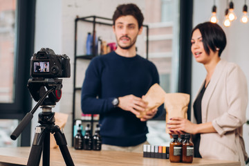 cheerful man and woman holding parsels and posing to the camera. blurred background
