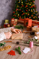 Close up shot of woman prepearing for winter holiday season at her workspace, wrapping christmas presents for family members. Christmas preparation concept. Crop, copy space.