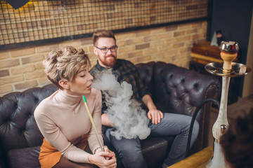 cheeerful ginger man is looking at blond girl who is smoking hookah. closeup photo. love. guy is falling in love