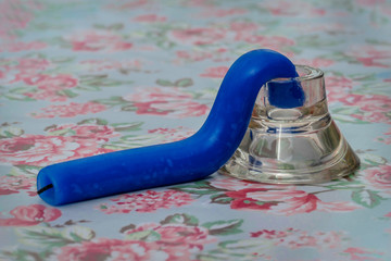 Durch Hitze geschmolzene, verformte blaue Kerze in einem Kerzenständer aus Glas, auf einem...