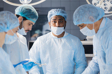 Indian surgeon in medical scrub suit looking extremely shocked and surprised as if he has done...