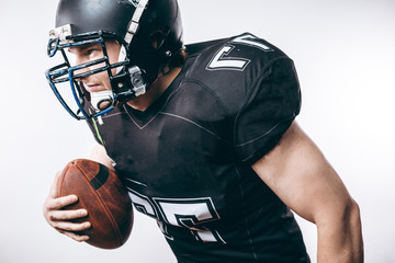 Emotional American football centre forward player in black protective uniform throwing a ball,...