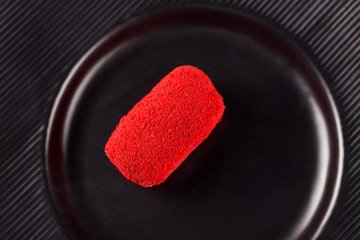 miniature cake-potatoes with red sprinkles on a black plate. Top view.