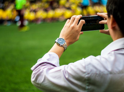 Man in work uniform Watch and shoot football competitions beside football field