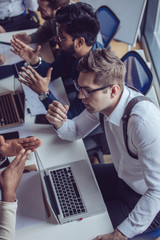 Multiethnic group of business men discussing strategic meeting at office, using smartphone laptop and tablet. Startup or teamwork concept. Top view