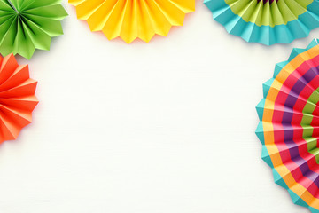 Festive and party background with colorful paper circle fans over wooden white background. Copy...