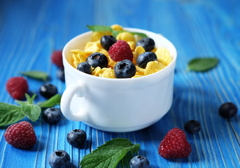 Cornflakes with berries raspberries and blueberries on blue wooden background.