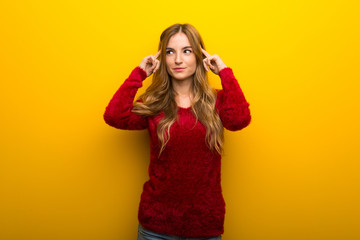 Young girl on vibrant yellow background having doubts and thinking