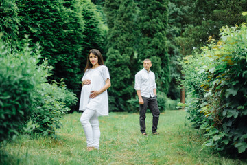 Fototapeta na wymiar Happy and young pregnant couple hugging in nature