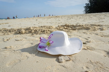 Fototapeta na wymiar Women's sun white hat with a flower lying on the beach sand by the sea.