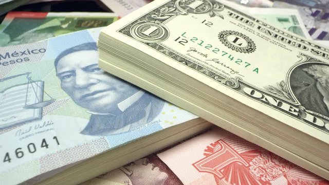 Panning over 1 dollar USD bill to Veinte Pesos on pile of bills.