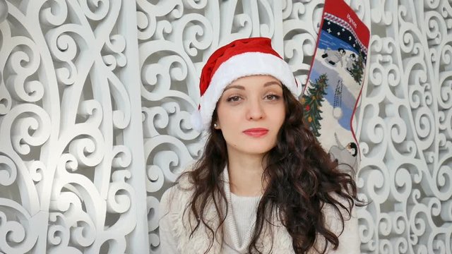 holidays and people concept - beautiful sexy woman in santa hat and and curly hair smiling against the backdrop of Christmas decor