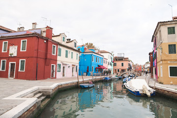 Fototapeta na wymiar Tourism in Venice, Burano Island, colored architecture, canal and boats. Trip to the island of Venice.