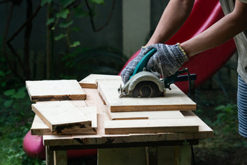 DIY sawing wood in the garden using handheld electrical saw