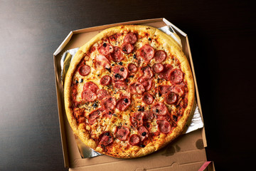 double cheese pizza from whole Pizza in a cardboard box dark table background.