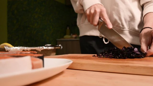 Closeup of the hands of a girl at the home kitchen on a wooden cutting board small cherry tomatoes. Home cooking