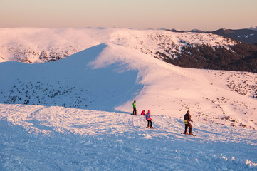 Snowboarders on top of a mountain at sunrise on a frosty winter morning. Snowboarders on the top of...